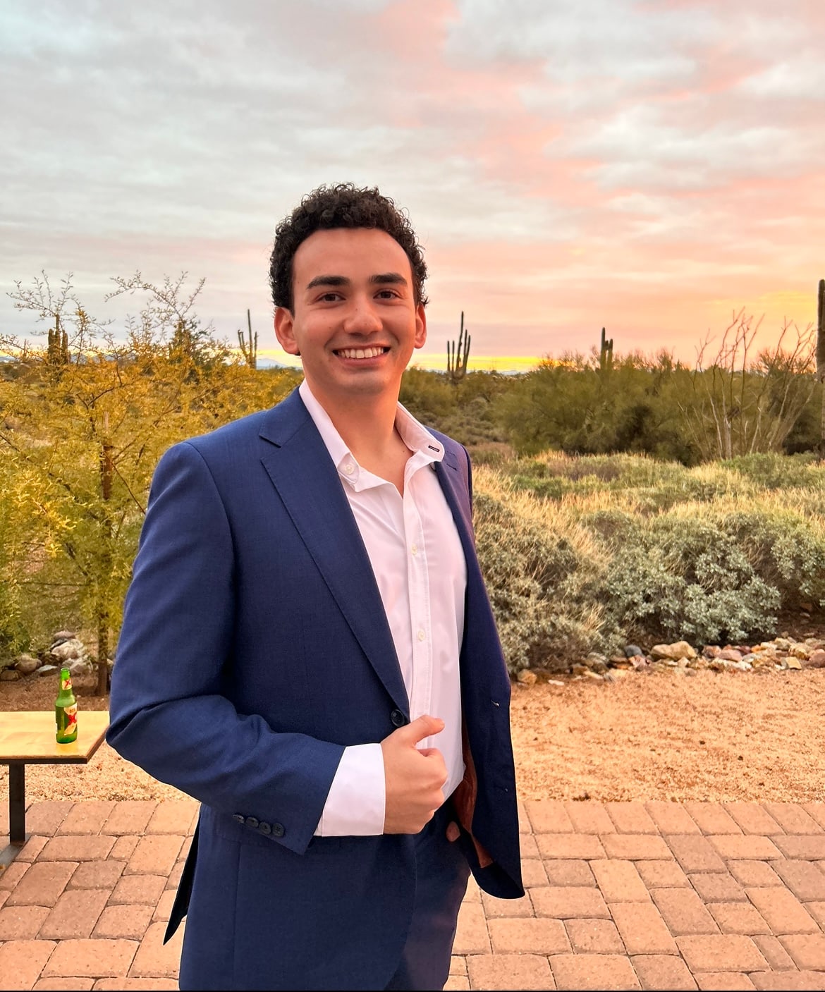 Stephen Leakos in a navy suit at sunset